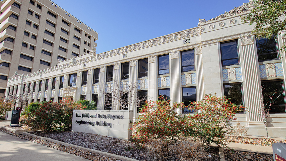 long, low two-story building with exterior ornate stonework carvings and tile featuring a sign in front with the words H.J. (Bill) and Reta Haynes Engineering Building