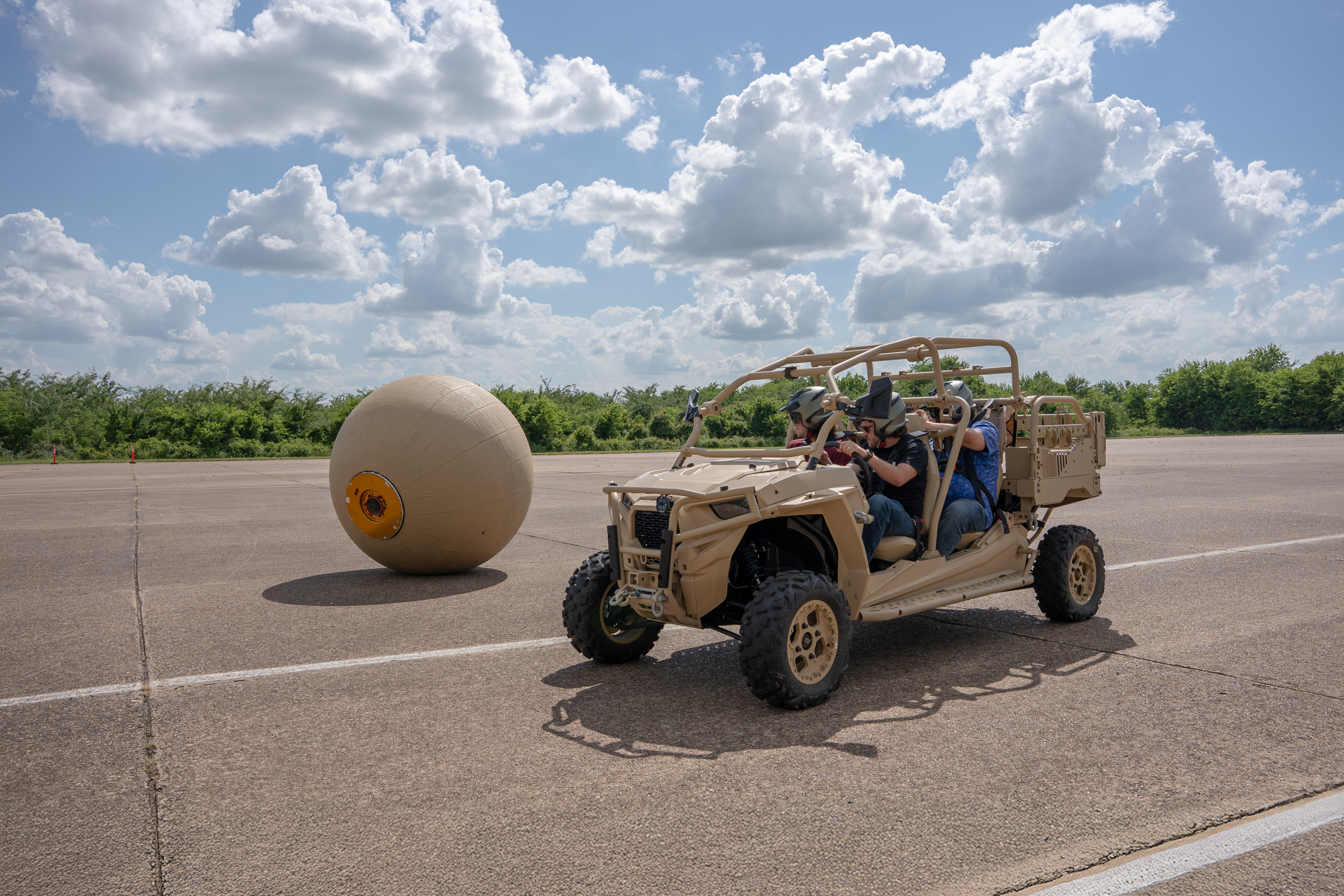A vehicle with three people inside next to RoboBall in a parking lot.