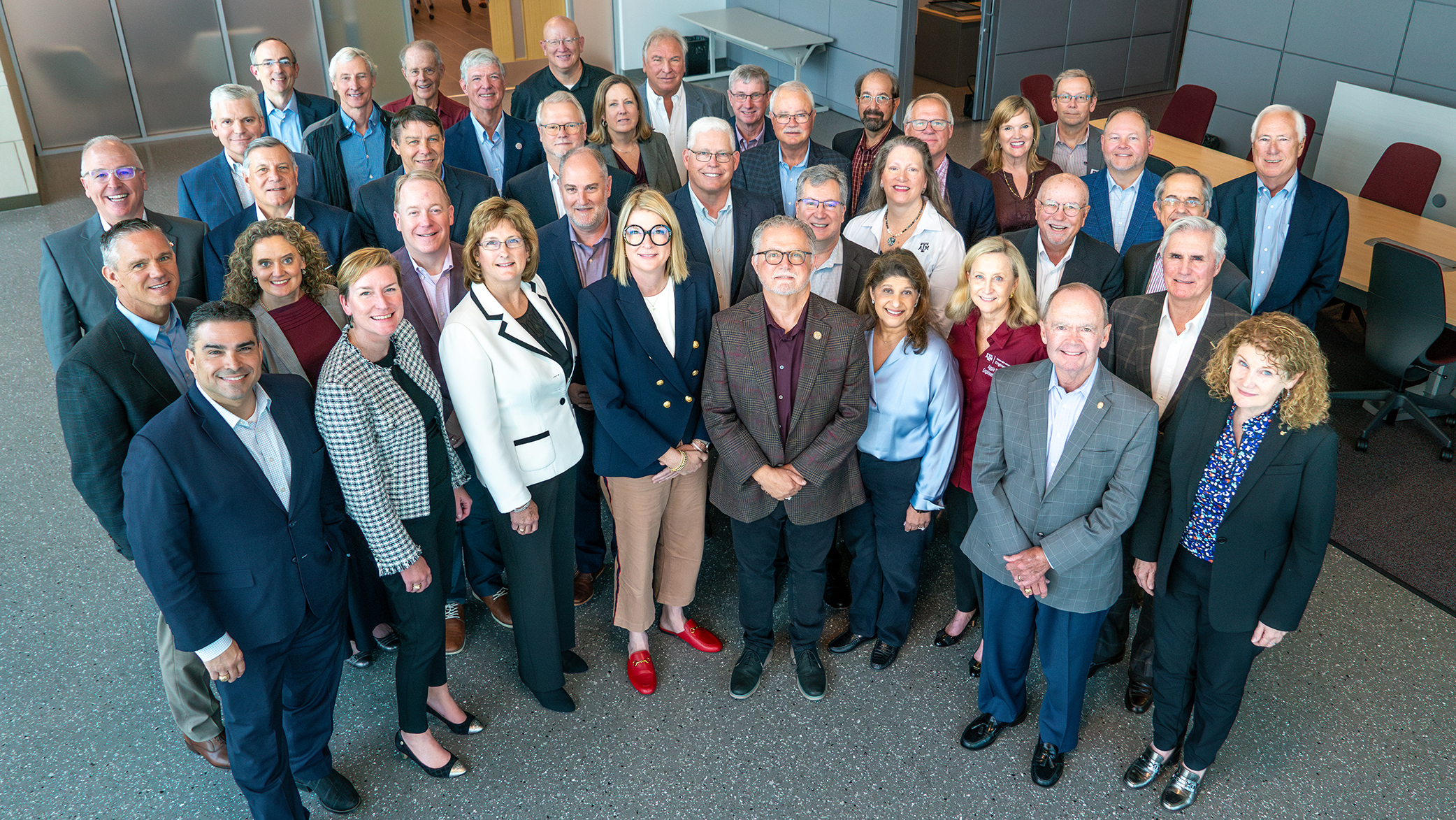 thirty-nine nicely dressed people looking up at an overhead camera and smiling