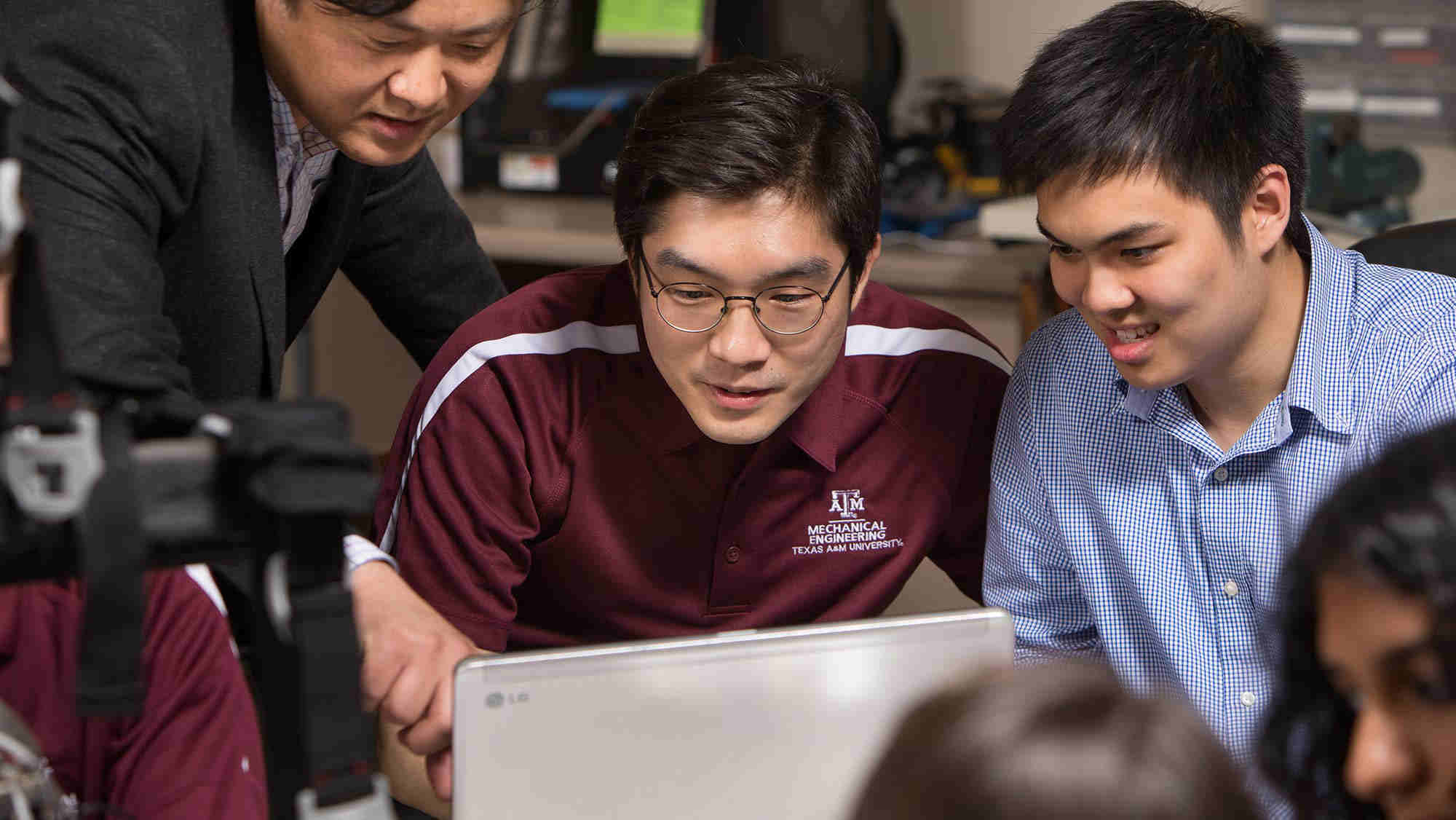 engineering student and professor around a computer laptop