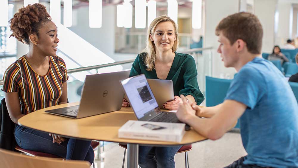 Two female and a male students talking.