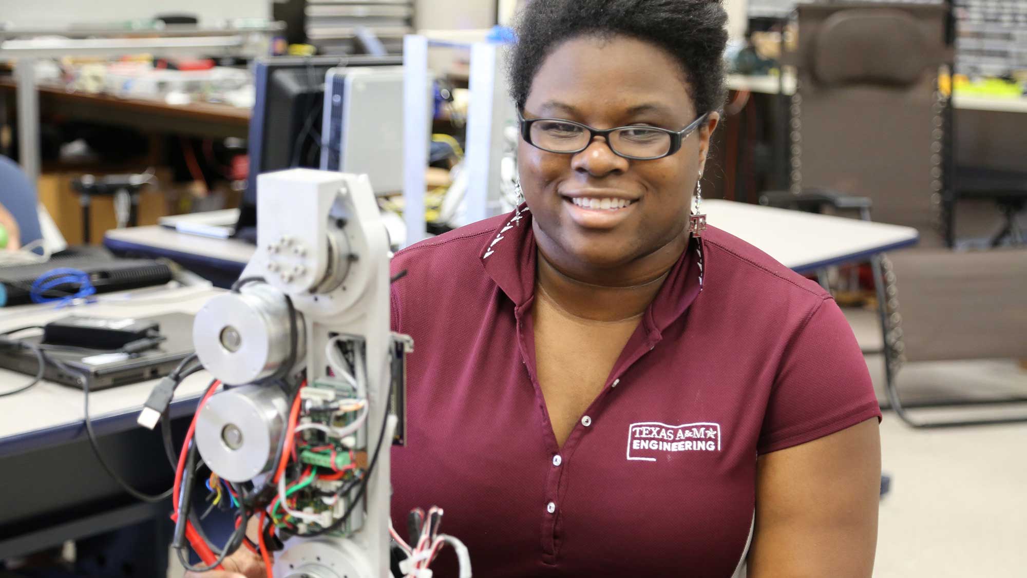 smiling engineering student sitting next to her project