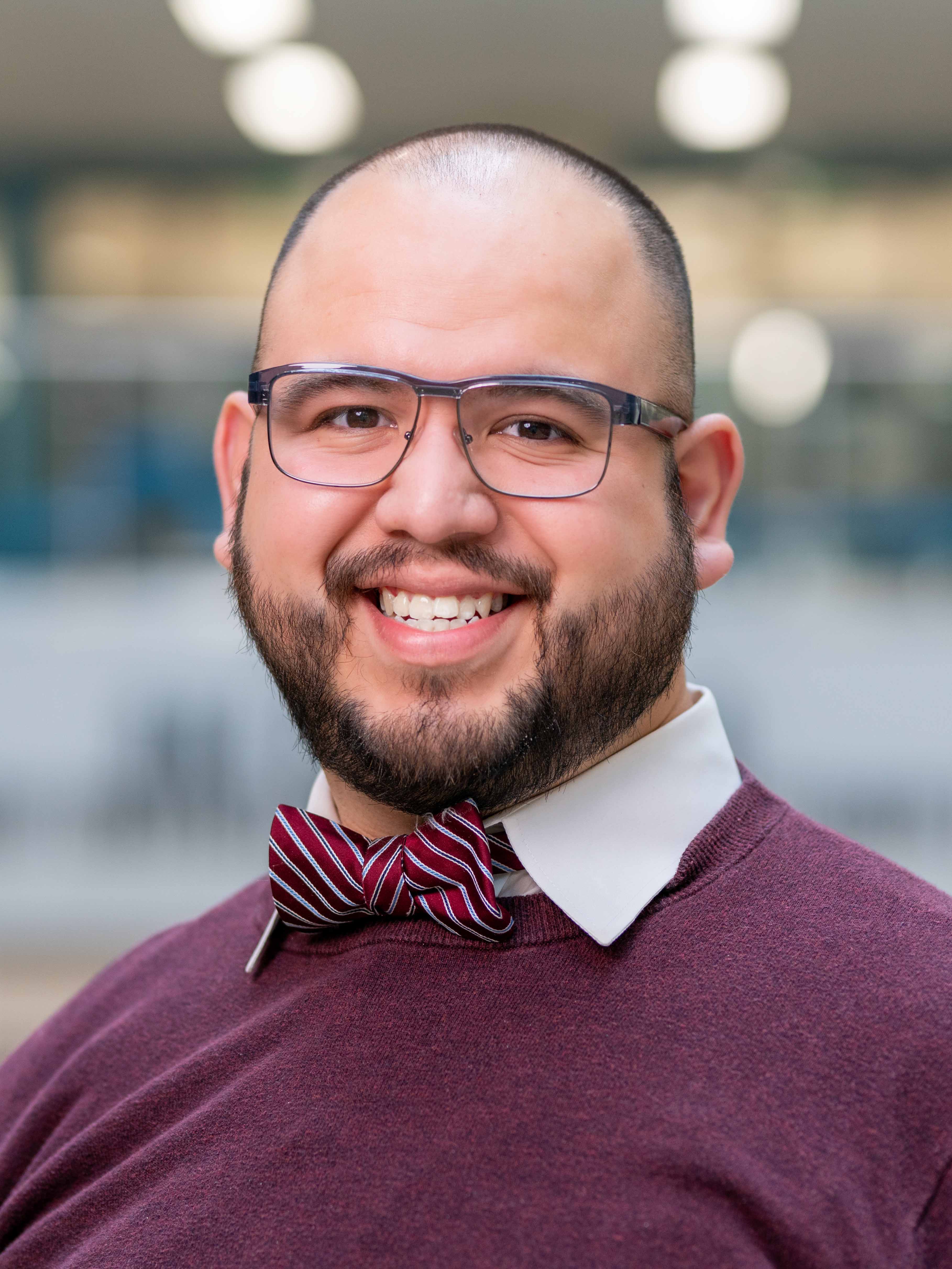 Justin Elizalde wearing a white-striped maroon bowtie and maroon sweater with white collars. 