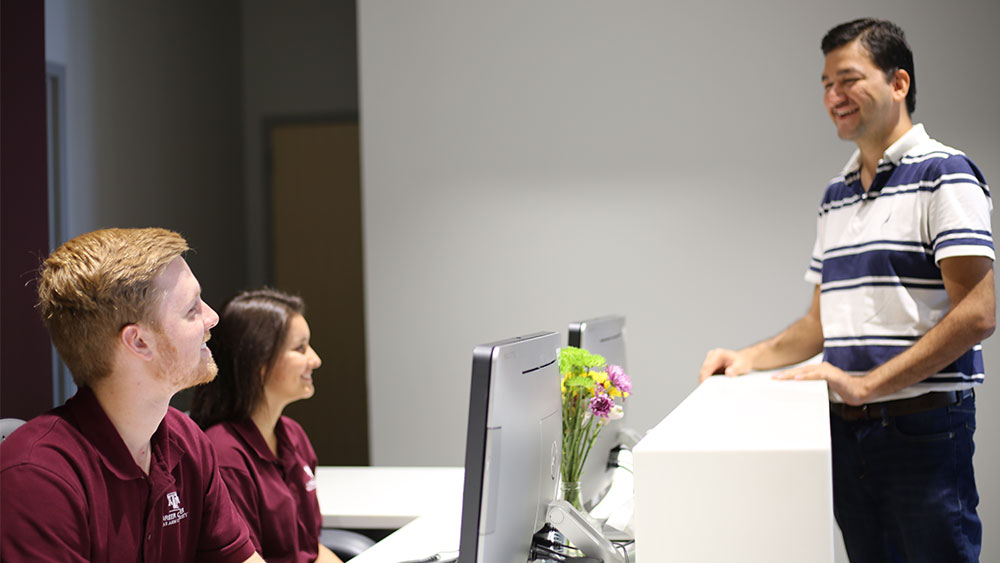 Student workers help another student at the career center front desk. 