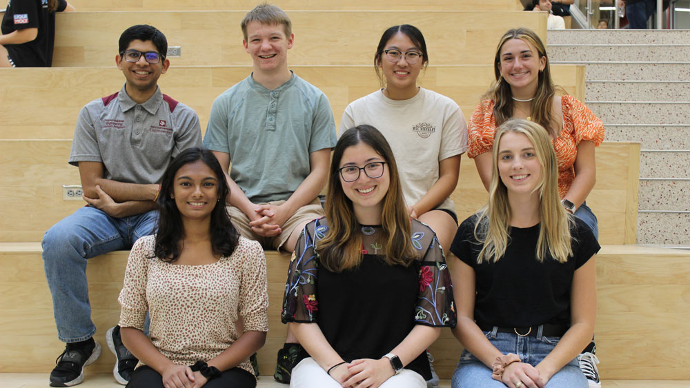 Seven students a part of the 2023-2024-ambassadors sitting on the learning stairs in the Zachary Engineering Education Complex.