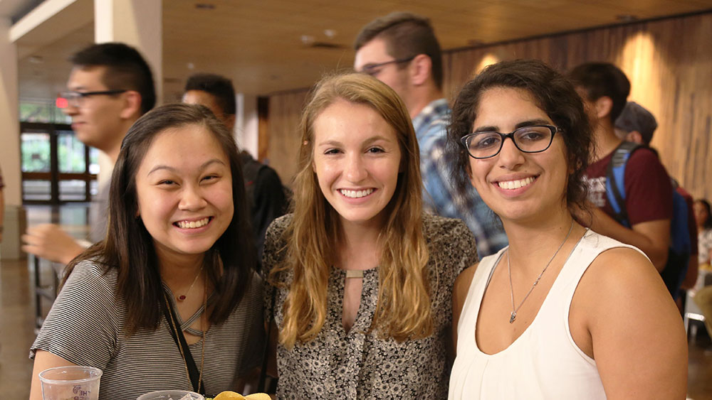 Three female first generation students smile