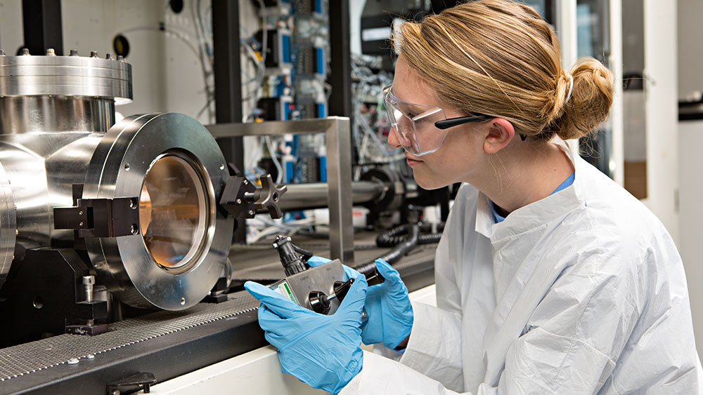 A female grad student in a white lab coat does research