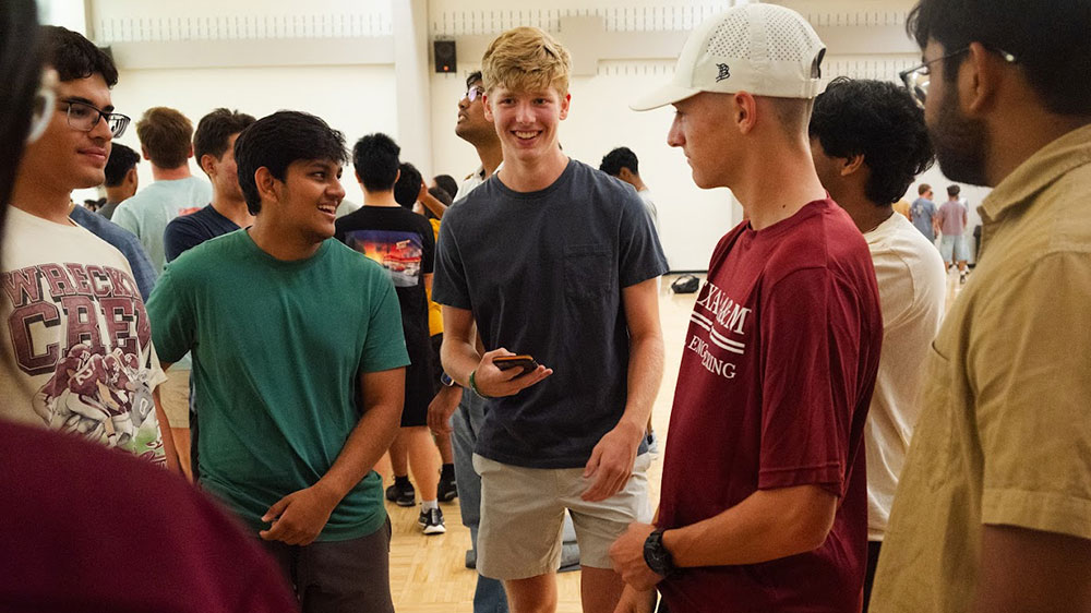 several students in a large room laugh and talk with each other