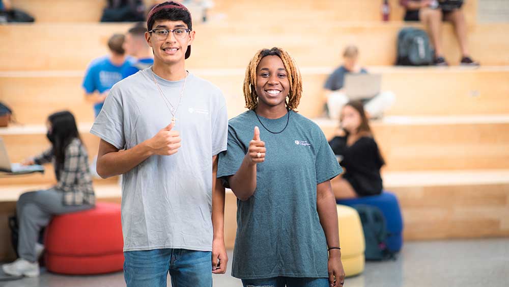 Two people smiling with a thumbs up.