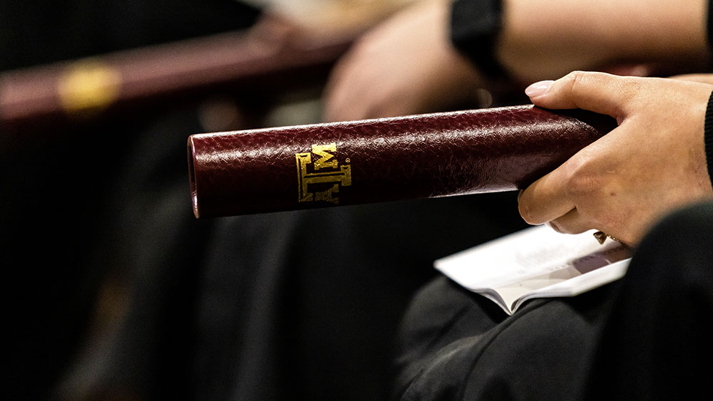 Hand holding a graduation certificate tube