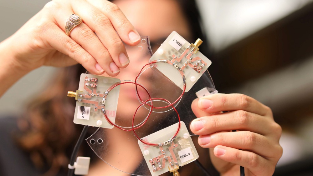 Researcher holds imaging technology with an Aggie ring on