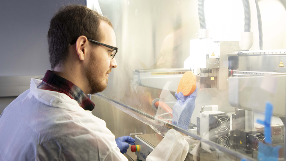 Student in lab next to plexiglass viewing area