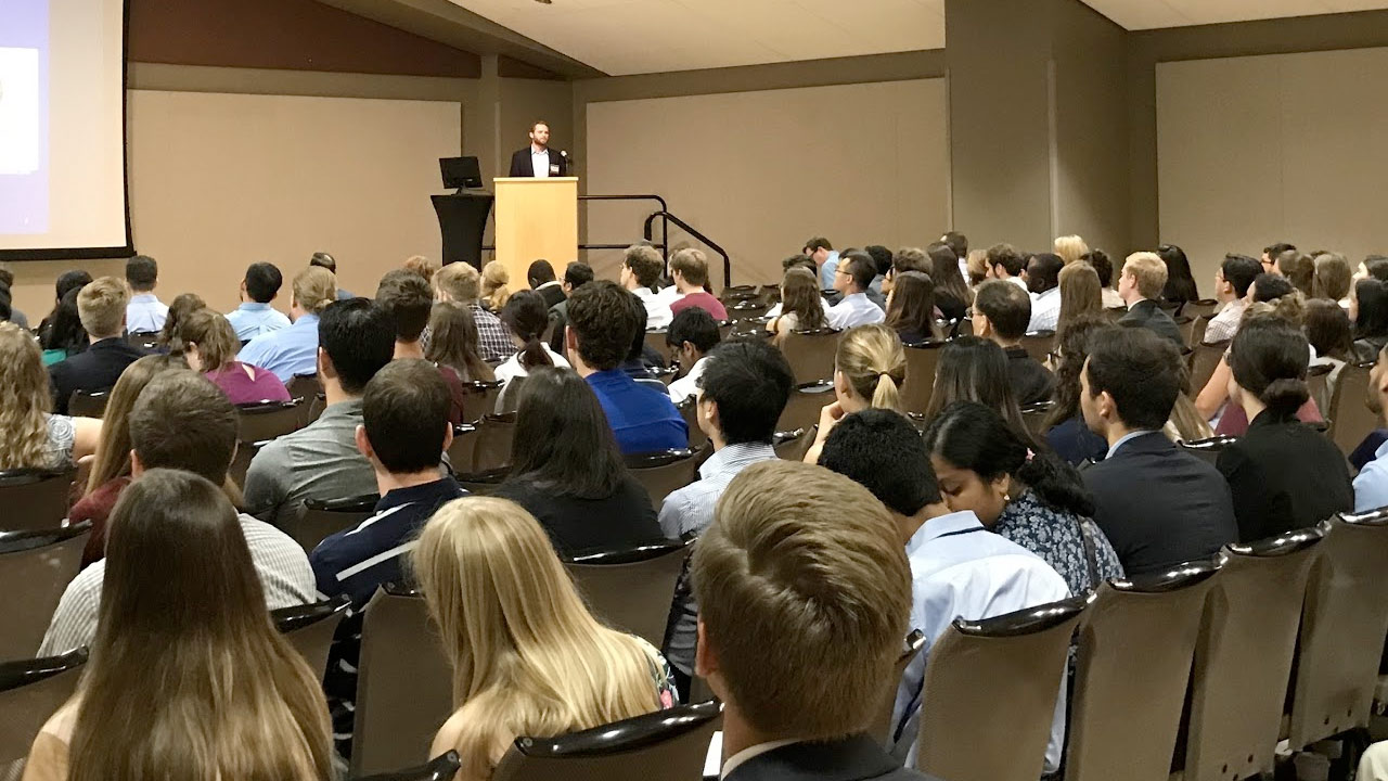 Large group of students gathered in a conference room listening to a grad admissions presentation