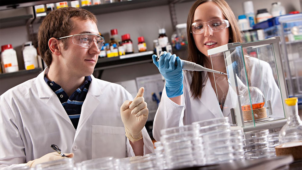 Biomedical students in white coats researching in a lab setting