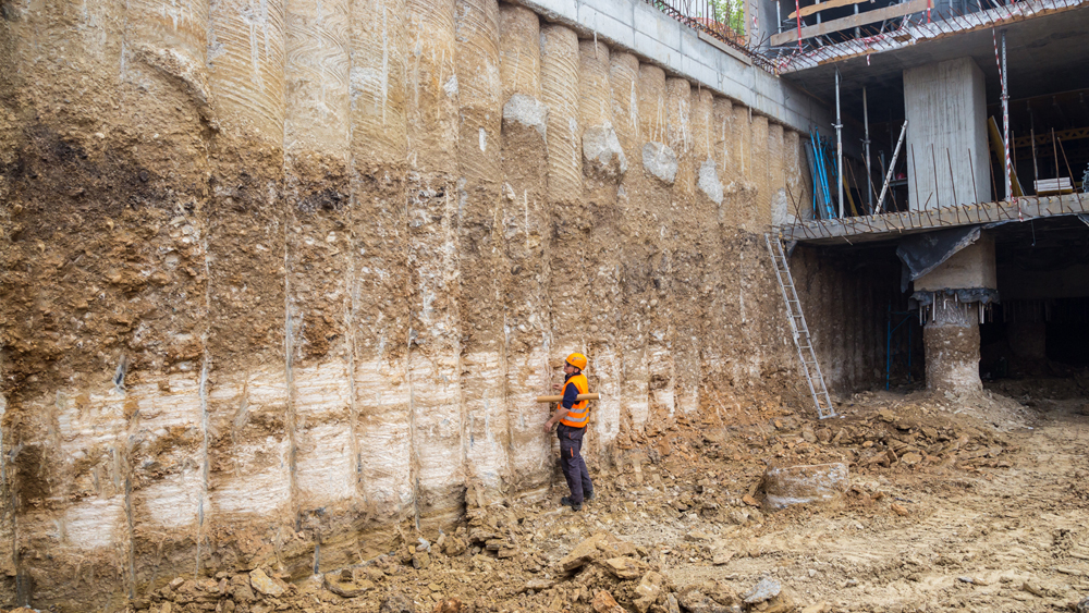 Man standing in front of layers of dirt at a construction site