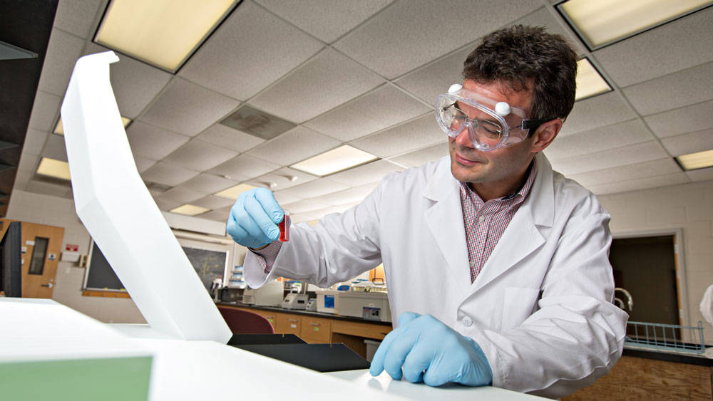 Researcher stares at vial.