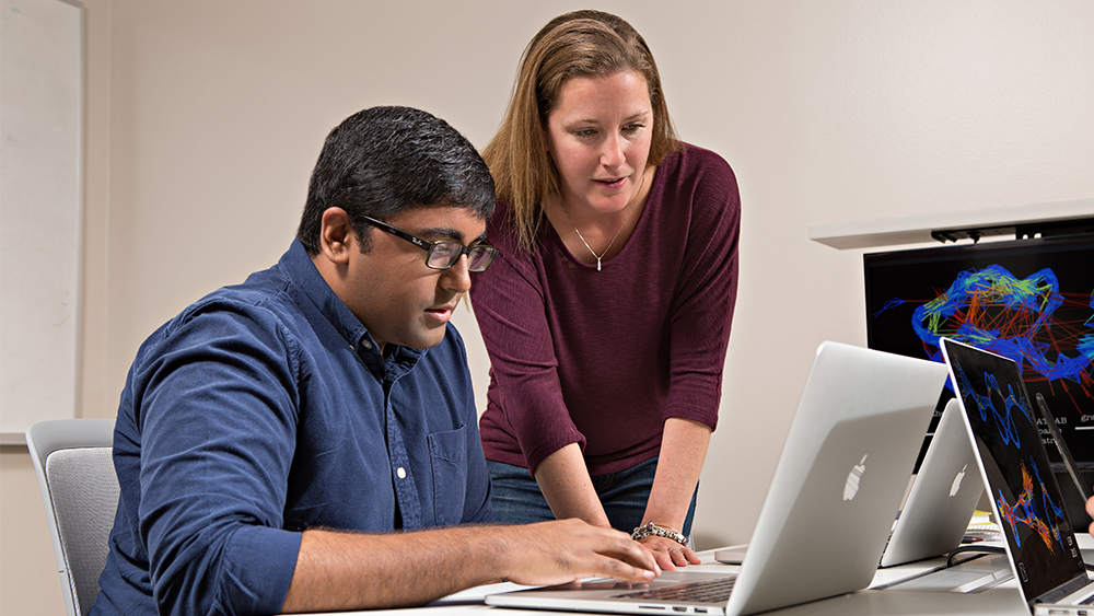 Image of two students interacting with a laptop.