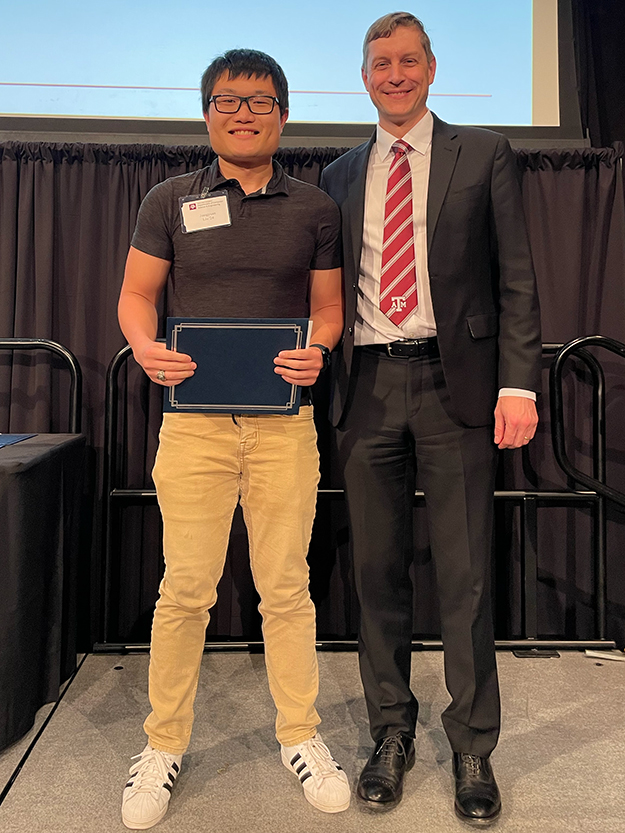 Student holding award while standing next to a faculty member