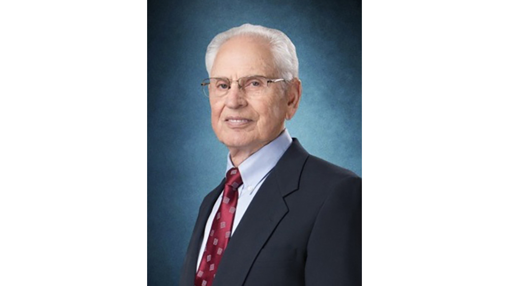 An individual in a dark suit, blue shirt and red tie.