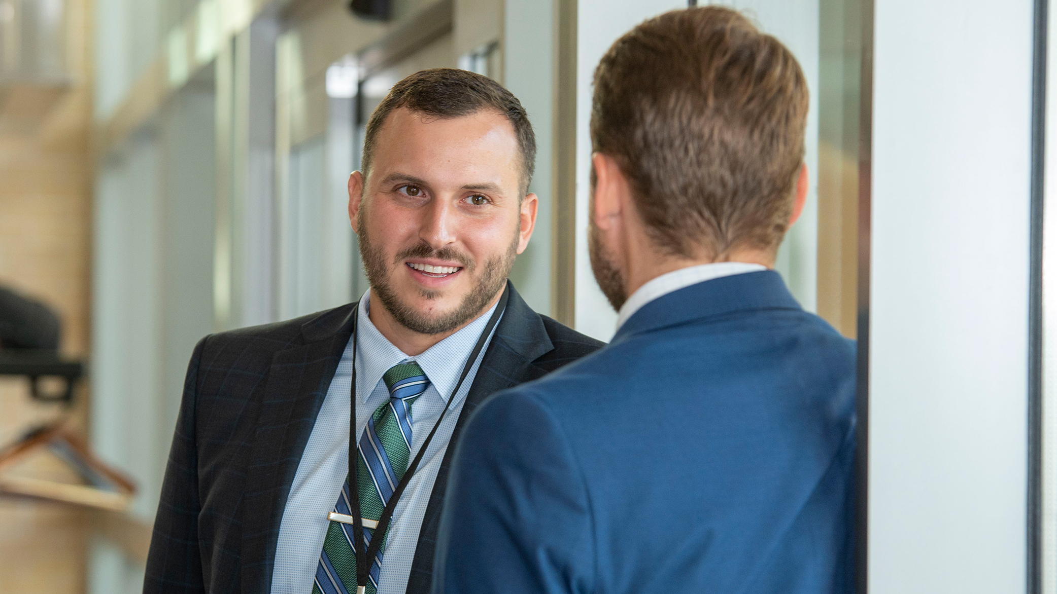 two people dressed in business attire talking in a large indoor space