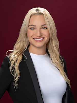 Woman with long blonde hair and dressed in professional attire smiles at the camera.