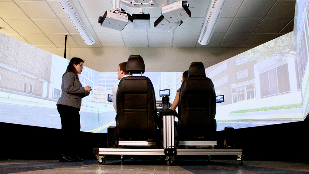 Dr. Zahabi speaks with two students using the driving simulator