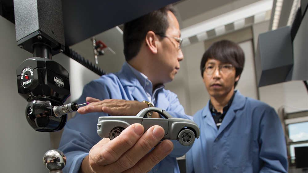 Professor and student look at product of a 3D printer. 