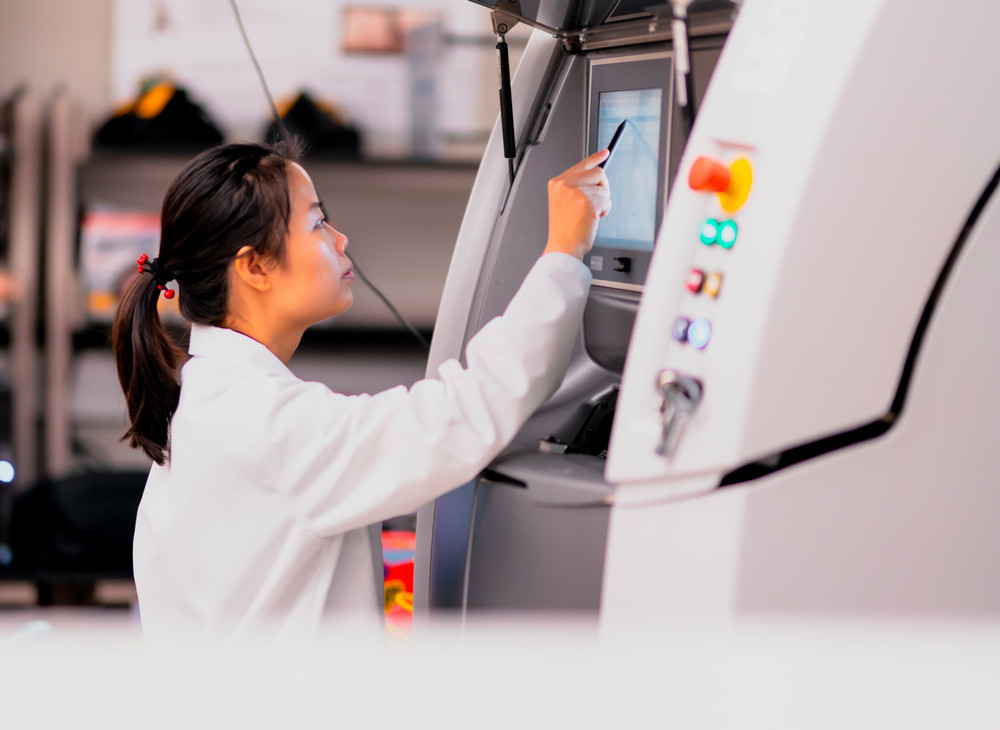 a woman using a machine in a lab.