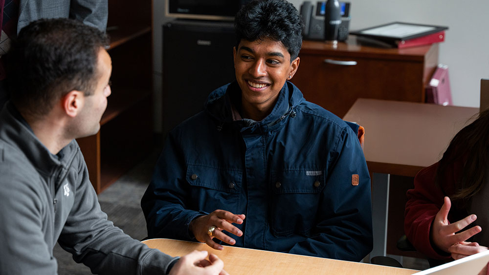two people seated around a table and talking