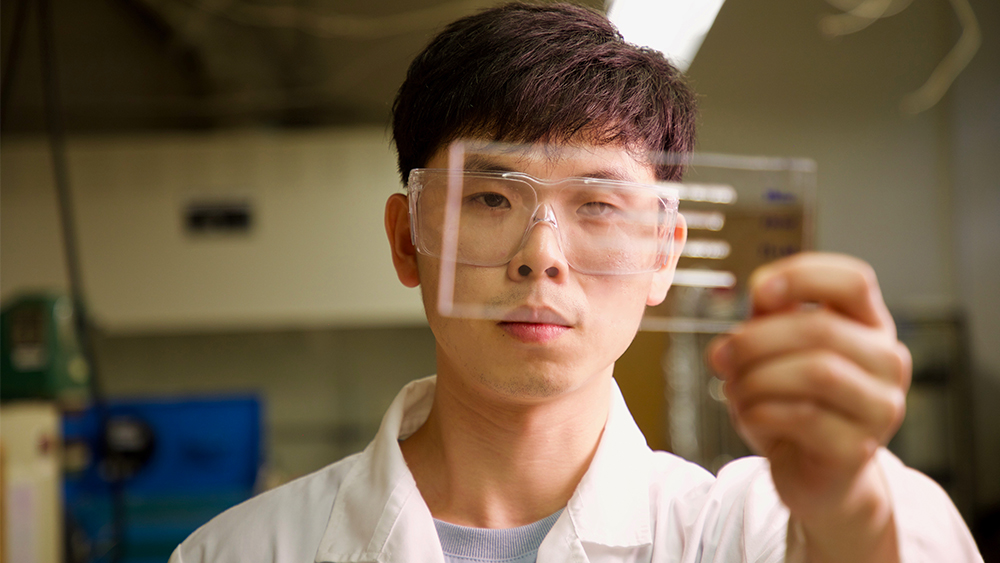 A male student examines a material in the lab.