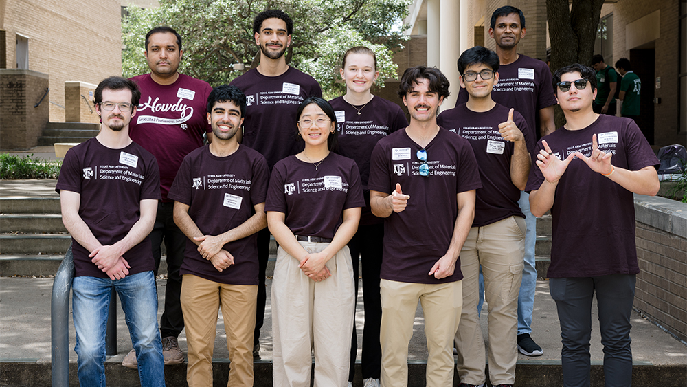 A group of people stand together outdoors, all wearing maroon shirts with “Department of Materials Science and Engineering” printed on them.