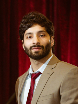 Man standing in a suit and tie in front of a background