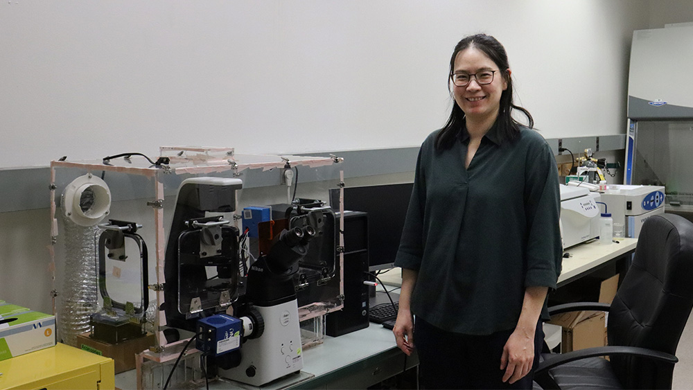 A woman stands in a lab in front of a machine