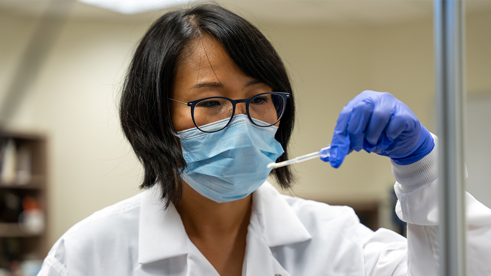 Researcher in lab coats using a dropper in a lab