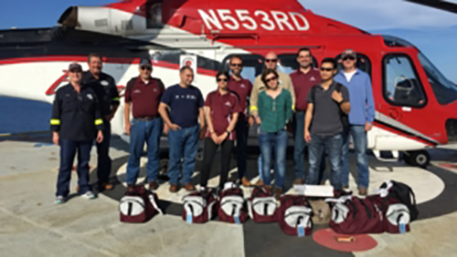 A group photo in front of a helicopter