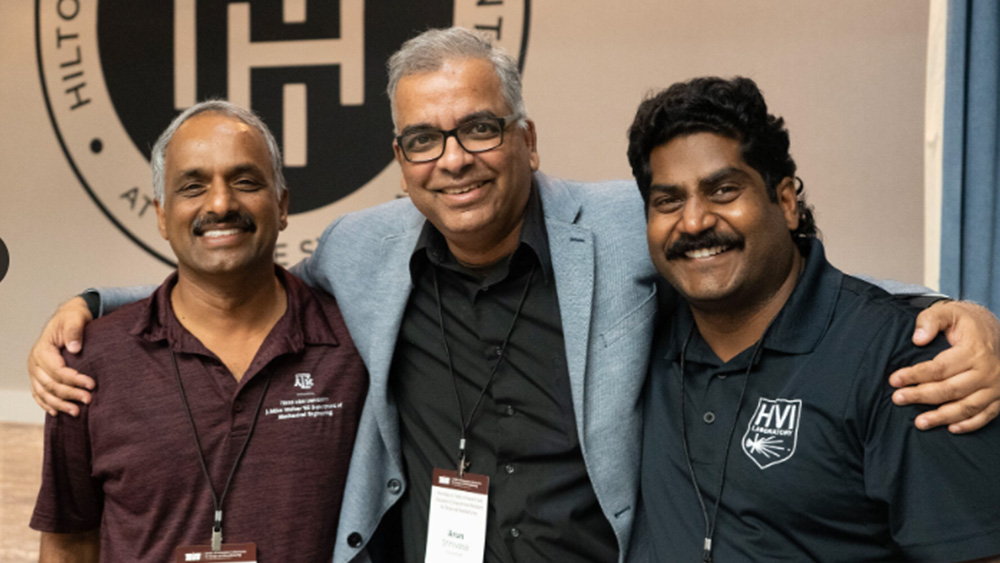 Three men smiling with arms around each other. 