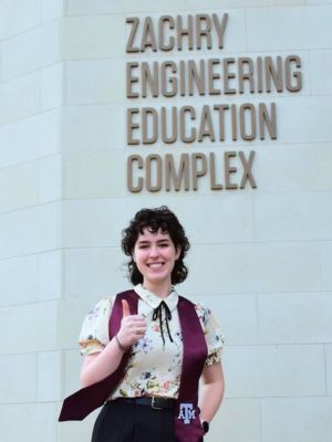 A woman posing with thumbs up in front of a sign that says "Zachry Engineering Education Complex."