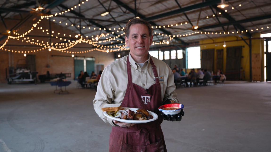 A man holding a plate in a wooden ballroom.