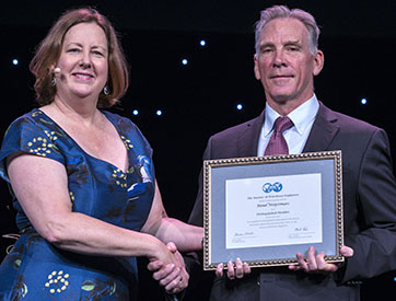 Janeen Judah and Ruud Weijermars share a handshake as Weijermars holds framed award