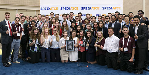 over 50 members of the student chapter at Texas A&M stand and kneel in a group around framed award