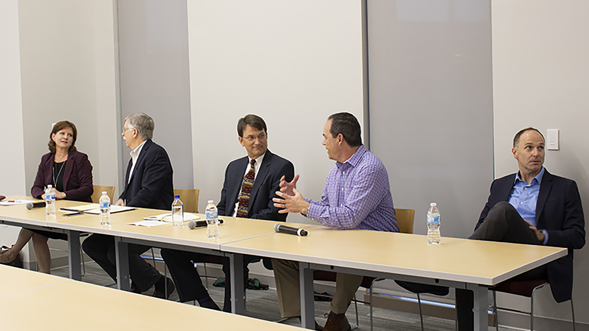 Five industry experts, four men and one women, sit at a table in a line for the Experts Panel.