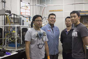 Group of students standing in the lab around lab equipment