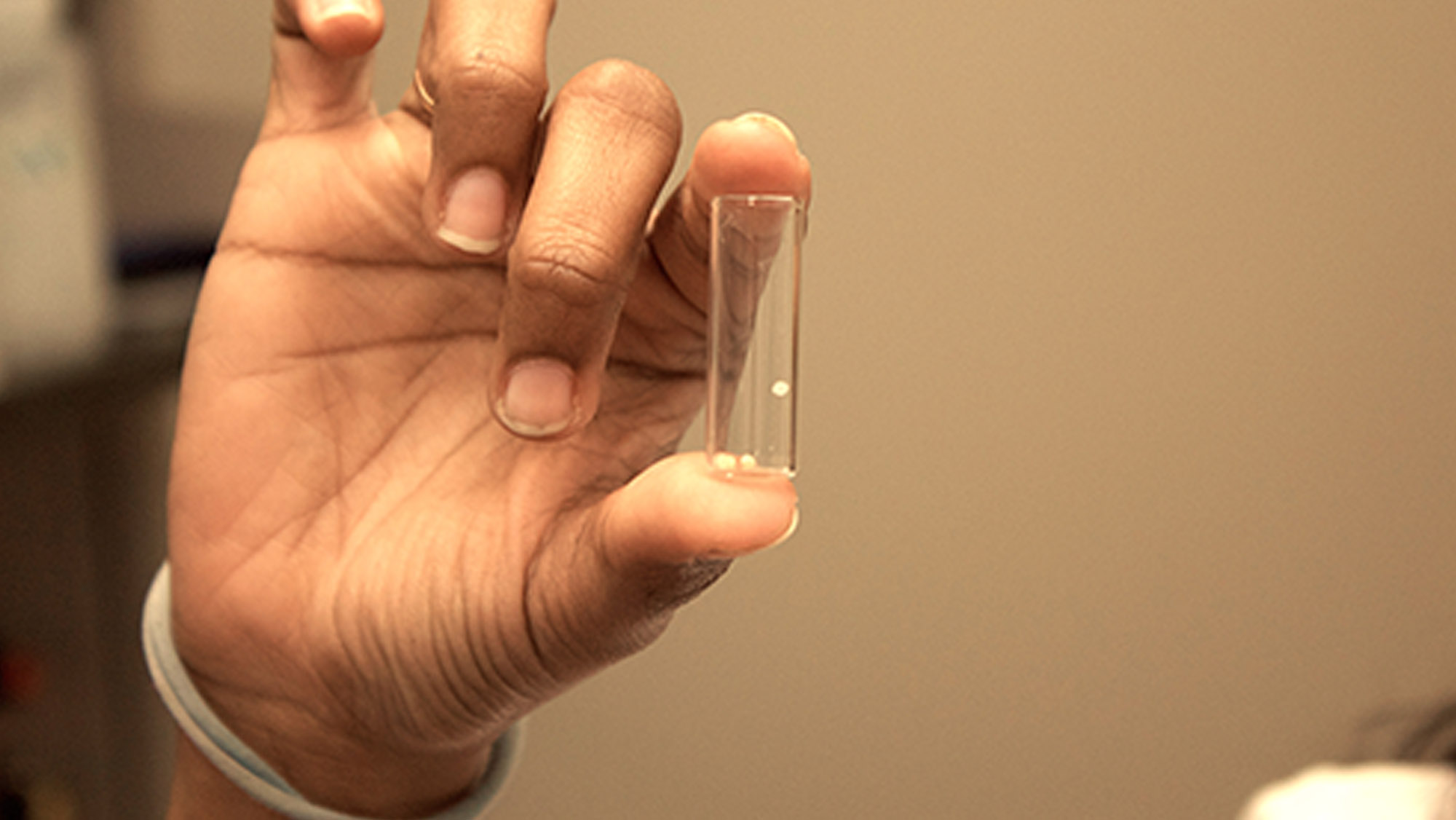 The "bubble" vaccine, a small, beige colored sphere, floats in a clear tube.