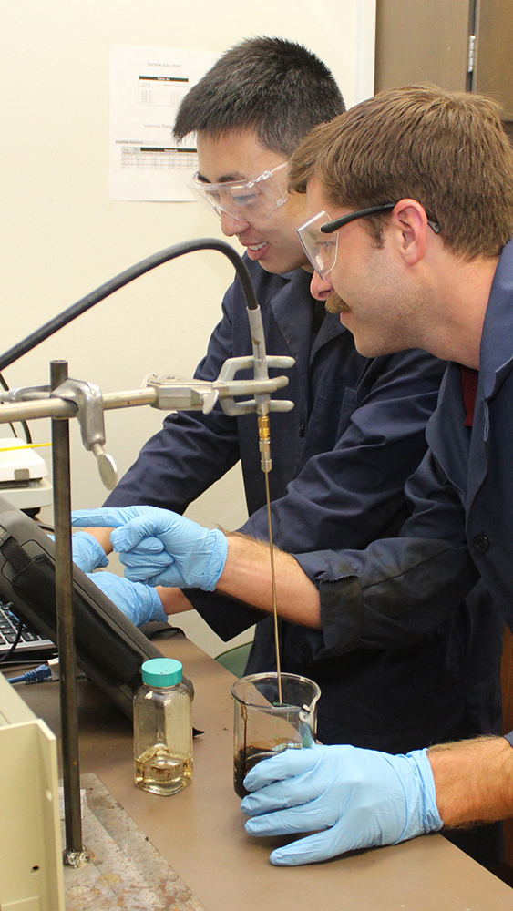 two students in a lab with computer and petroleum samples