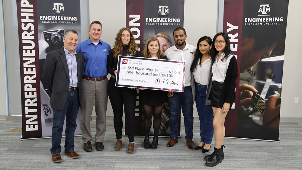 Members of SuperSocials from Swansea University pose for a photo with two judges and a check for $1,000.