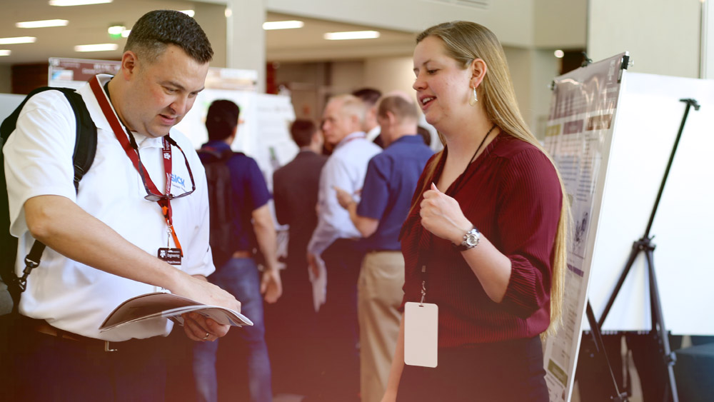 A female engineering student talking with an industry judge about her project.