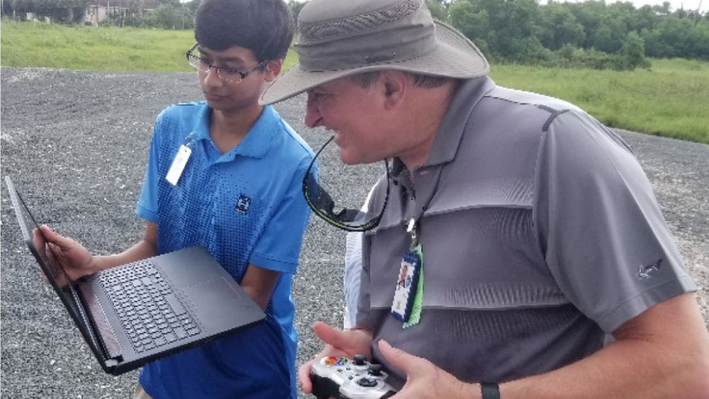 A student and NASA scientist look at a laptop.