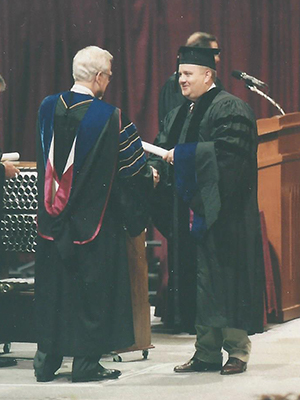 Dr. Brian Craig receives his diploma on stage at his PhD graduation. 