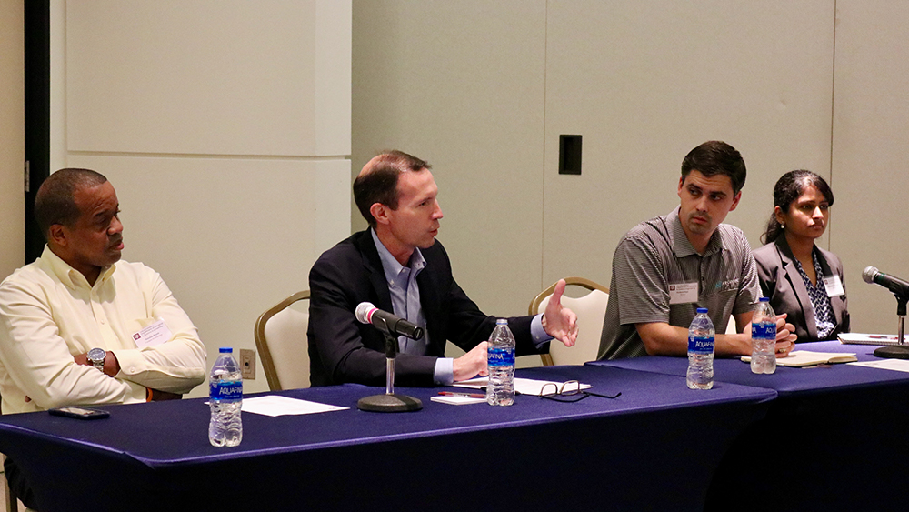 Four individuals sitting and speaking as part of a panel. 