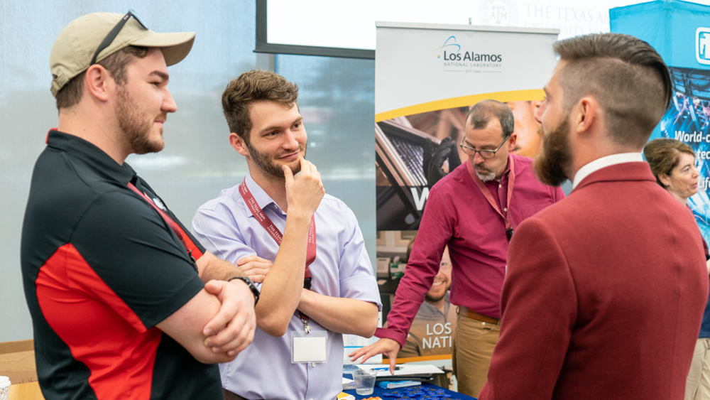 Students at the NSE Day career fair chat with technical representatives from companies and national labs.